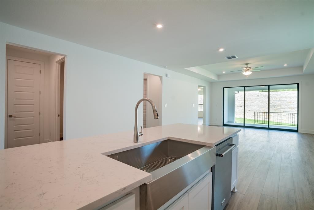 4612 Modena Bay Bend Leander, TX 78641 - Photo 20 of 34 Kitchen featuring white cabinetry, light wood-style floors, light stone countertops, a raised ceiling, and recessed lighting