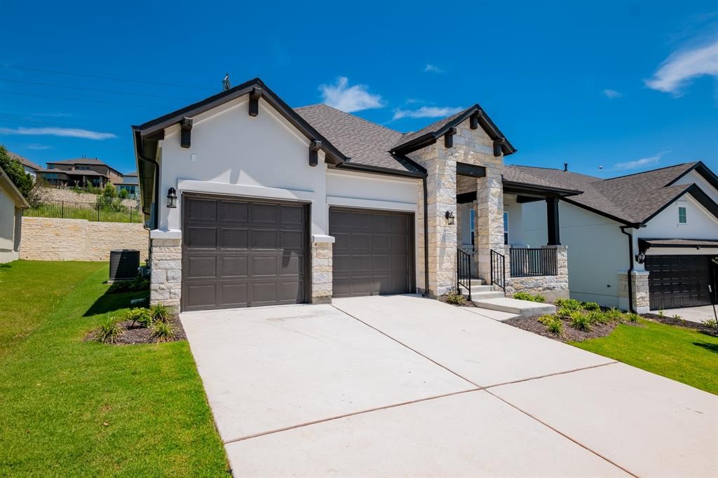 4612 Modena Bay Bend Leander, TX 78641 - Photo 2 of 34 View of front of house with stone siding, a front yard, concrete driveway, and stucco siding