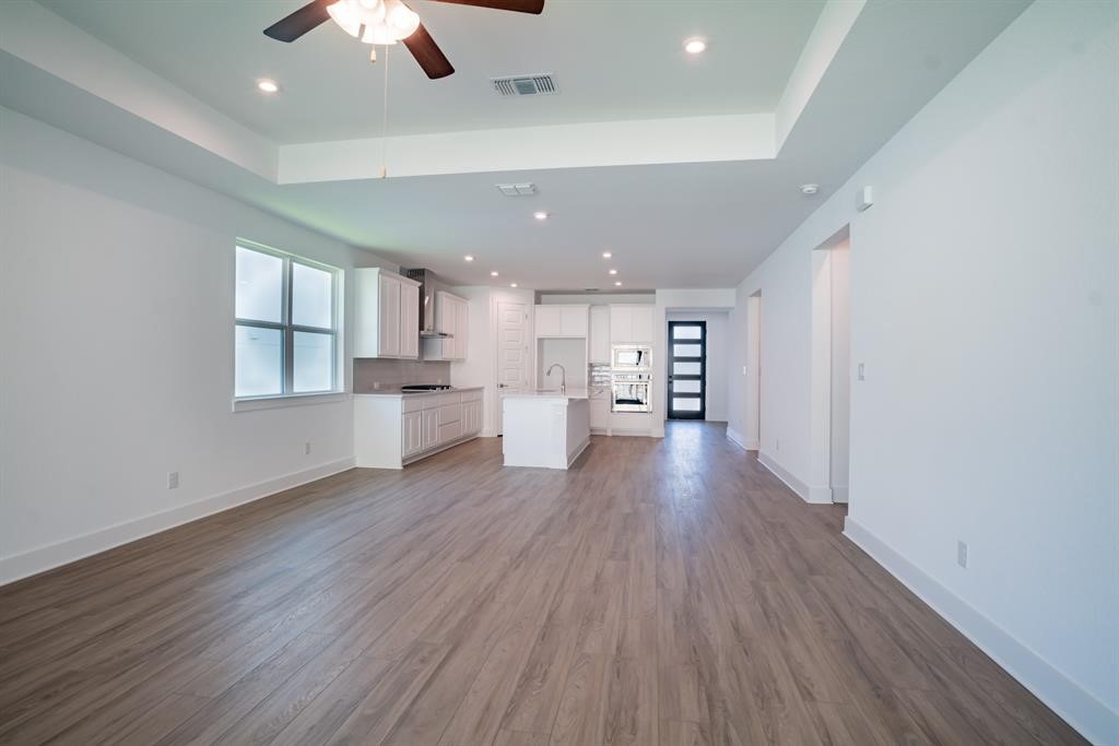 4612 Modena Bay Bend Leander, TX 78641 - Photo 23 of 34 Unfurnished living room featuring a tray ceiling, plenty of natural light, dark wood-type flooring, and recessed lighting