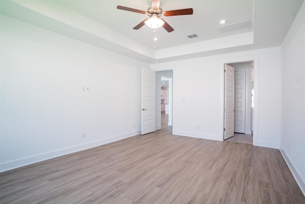 4612 Modena Bay Bend Leander, TX 78641 - Photo 27 of 34 Unfurnished bedroom with light wood-style floors, ceiling fan, a raised ceiling, and recessed lighting