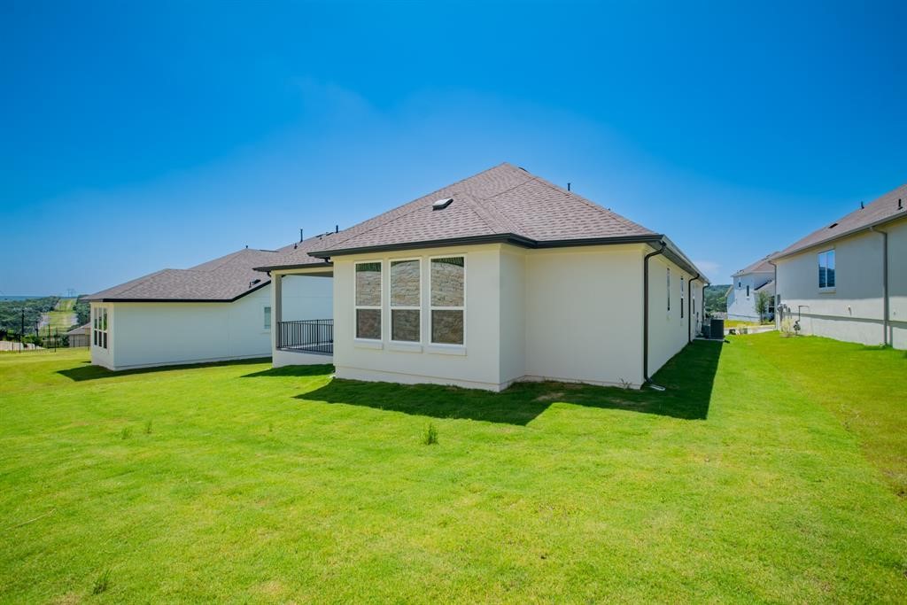 4612 Modena Bay Bend Leander, TX 78641 - Photo 30 of 34 Back of property featuring a lawn, a shingled roof, and stucco siding