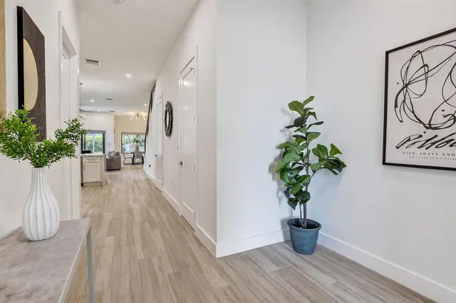 a view of a hallway with wooden floor and a potted plant