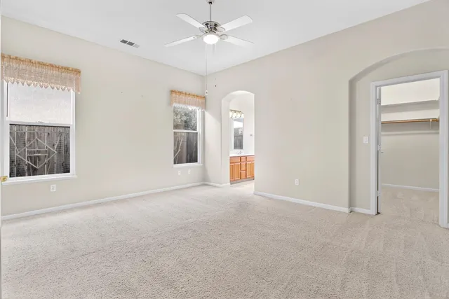 an empty room with windows and fan