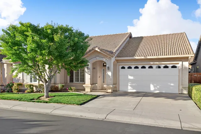 a front view of a house with a garden and trees