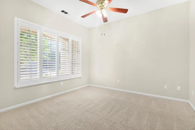 an empty room with a window and a fan