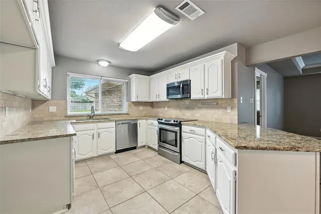 a kitchen with granite countertop cabinets stainless steel appliances a sink and a counter top space