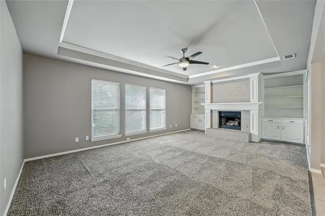 an empty room with windows and fireplace