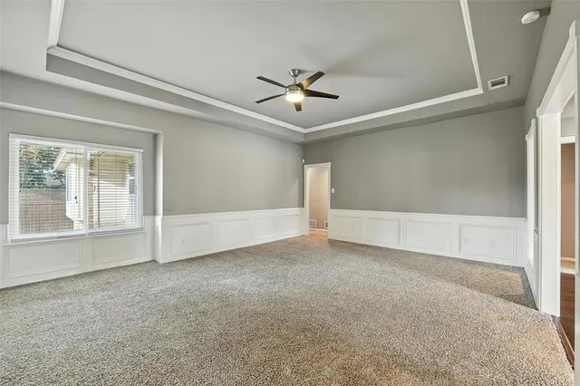 an empty room with chandelier fan and windows