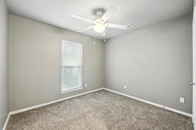an empty room with a window and a fan