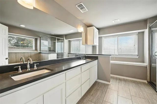 a large bathroom with a double vanity sink a mirror and a bathtub