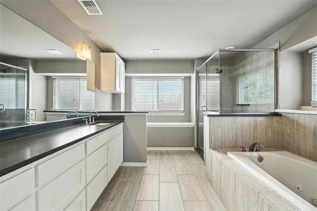 a spacious bathroom with a tub a sink and mirror