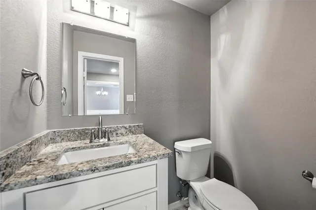 a bathroom with a granite countertop toilet sink and mirror