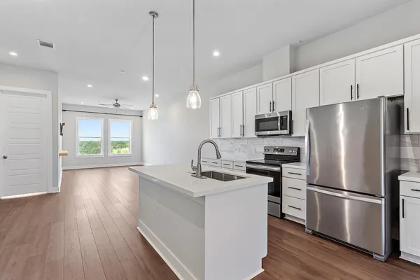 a kitchen with stainless steel appliances a refrigerator sink and wooden floor