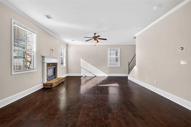 a view of an empty room with wooden floor fireplace and a window