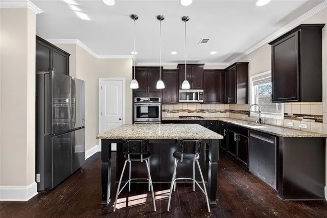 a kitchen with stainless steel appliances kitchen island granite countertop a table chairs sink and cabinets