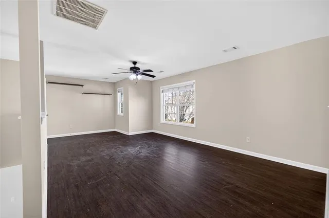 a view of an empty room with wooden floor and a ceiling fan