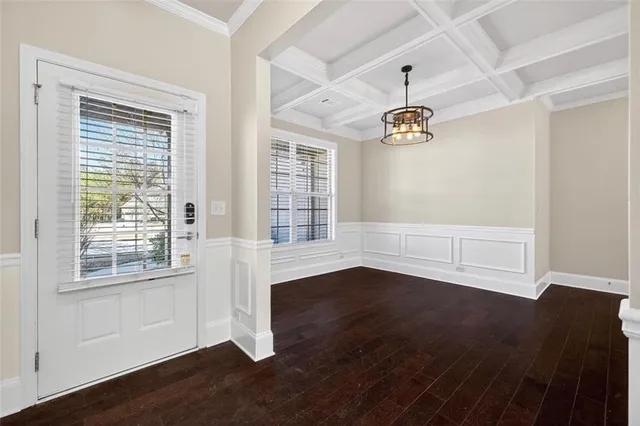a view of an empty room with wooden floor and windows