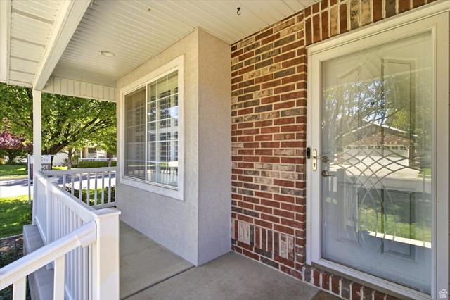 1089 West 2325th Street North Layton, UT 84041 - Photo 3 of 40 Covered front porch featuring stucco and brick siding, white railing, and a storm door with decorative glass