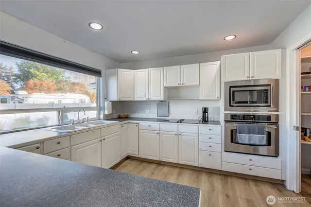 a kitchen with kitchen island granite countertop a sink cabinets and stainless steel appliances
