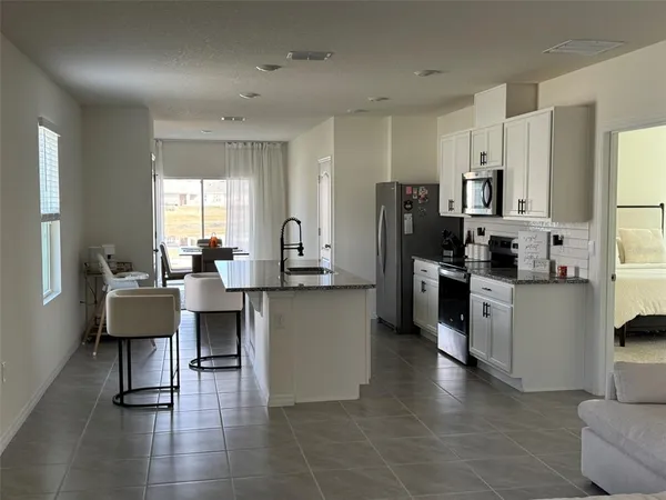 a kitchen with stainless steel appliances a refrigerator a stove a sink dishwasher and white cabinets with wooden floor