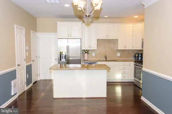 a kitchen with stainless steel appliances a refrigerator a sink dishwasher a stove and white cabinets with wooden floor
