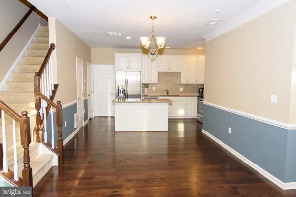 a view of a kitchen with kitchen island stainless steel appliances a sink and a living room view