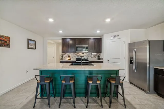 a kitchen with stainless steel appliances granite countertop a stove a sink a microwave a dining table and chairs