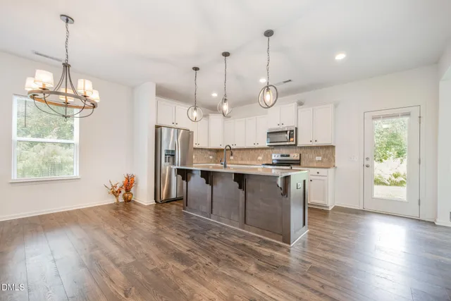 a view of a room with wooden floor kitchen view and a window
