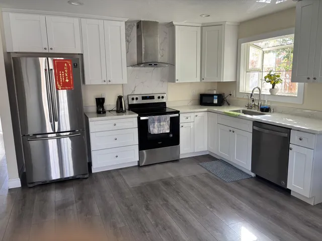a kitchen with granite countertop white cabinets and stainless steel appliances