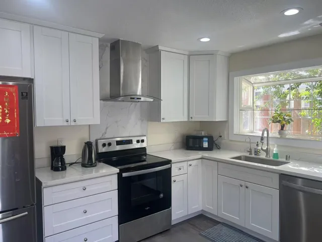 a kitchen with granite countertop white cabinets and white stainless steel appliances