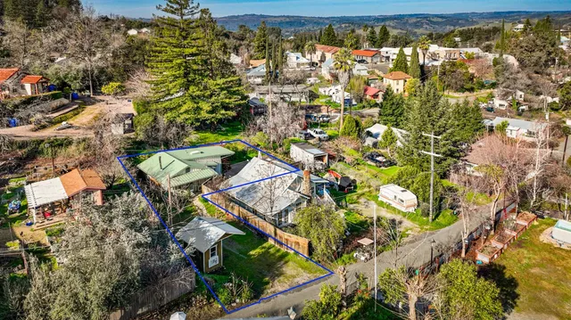 an aerial view of residential house with parking and trees