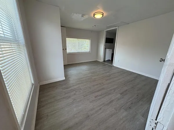 an empty room with wooden floor and windows