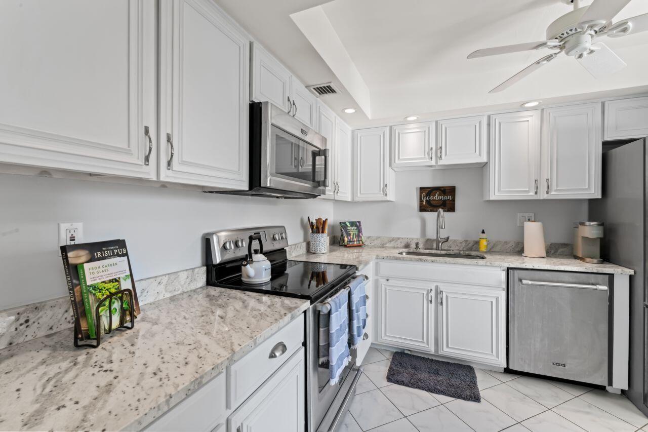 a kitchen with stainless steel appliances granite countertop white cabinets sink and a stove