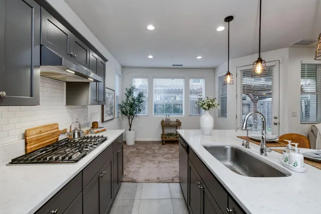 a kitchen with kitchen island granite countertop a sink a counter space appliances and cabinets