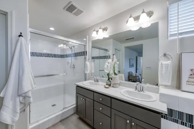 a bathroom with a double vanity sink mirror and shower