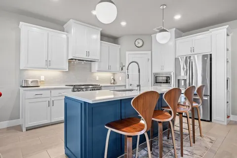 a kitchen with stainless steel appliances granite countertop a table chairs sink and cabinets