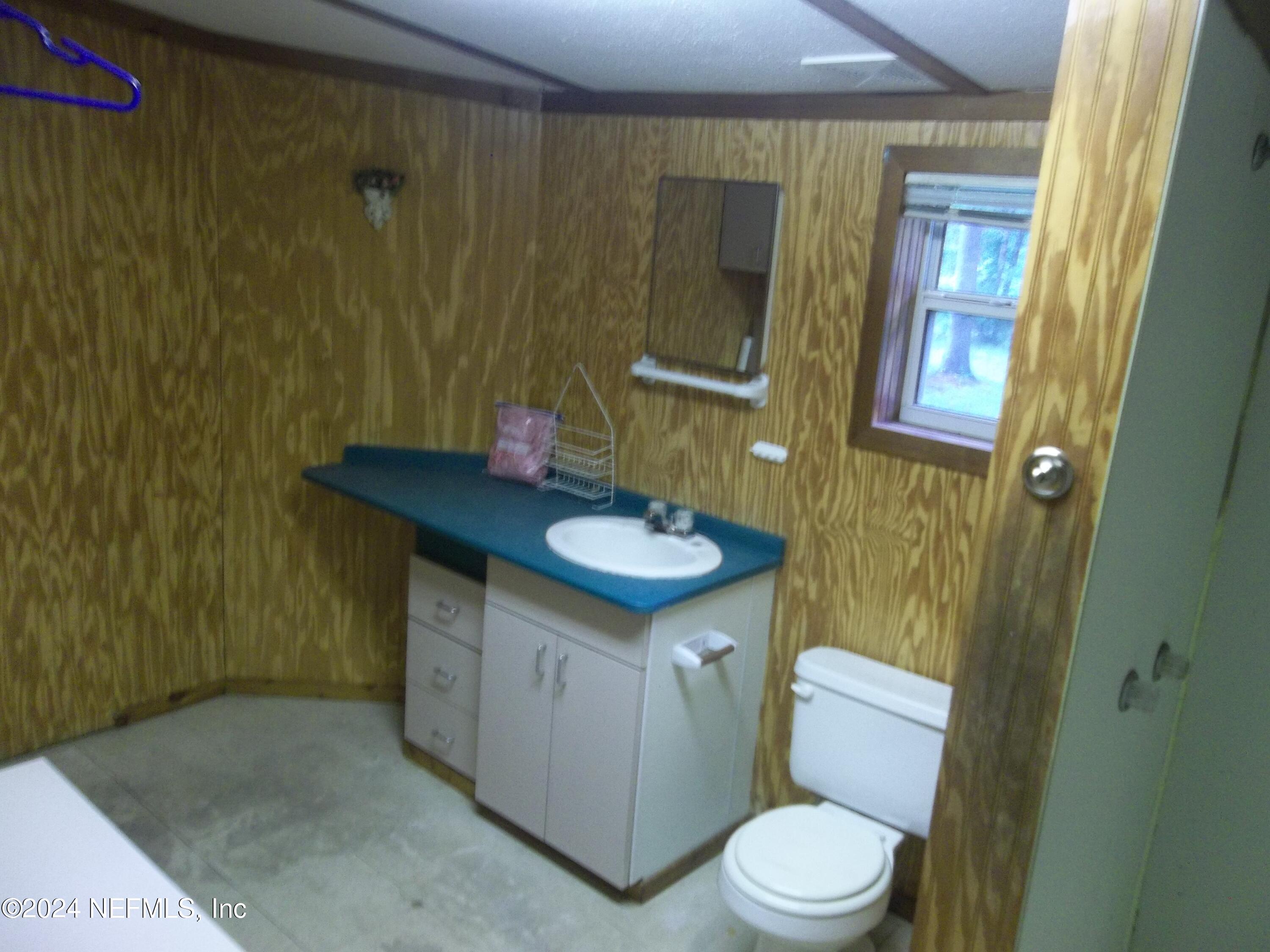 95182 Santa Juana Road Fernandina Beach, FL 32034 - Photo 19 of 20 a bathroom with a sink a toilet a mirror a vanity and shower