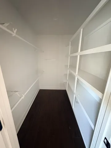 a view of an empty room with wooden floor and a ceiling fan