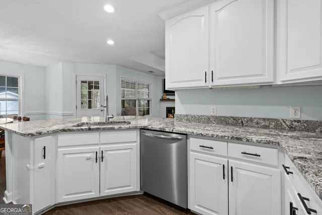 a kitchen with granite countertop white cabinets and a sink