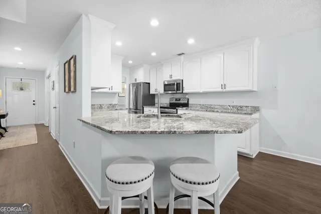 a kitchen with stainless steel appliances granite countertop a table chairs sink and cabinets