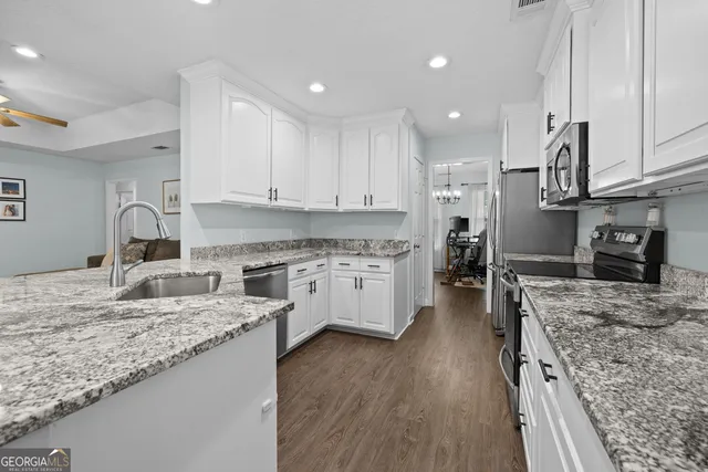 a kitchen with stainless steel appliances granite countertop a stove top oven a sink dishwasher and a refrigerator with wooden floor