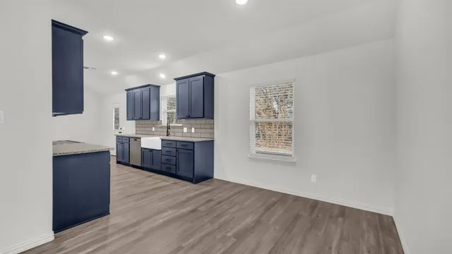 a large kitchen with stainless steel appliances granite countertop a large stove a sink dishwasher and a refrigerator with wooden floor