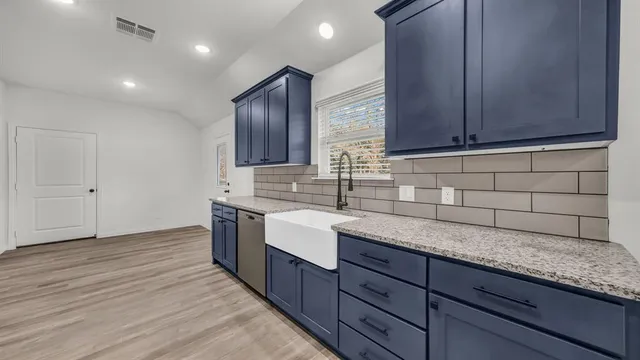 a kitchen with granite countertop wooden cabinets a sink and dishwasher