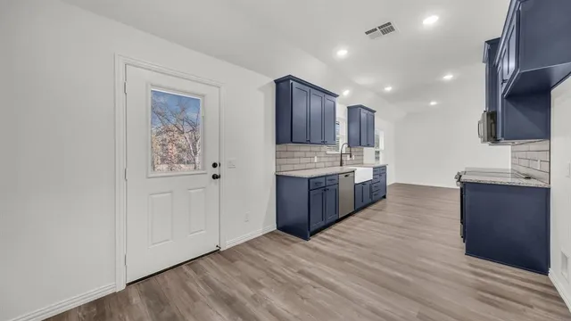 a large kitchen with stainless steel appliances a large counter top a sink and a stove