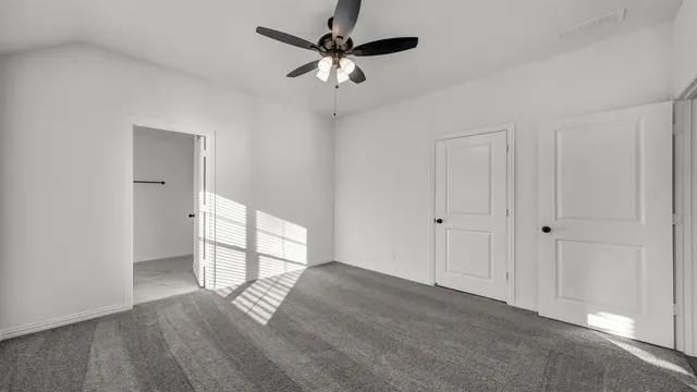an empty room with a ceiling fan and window