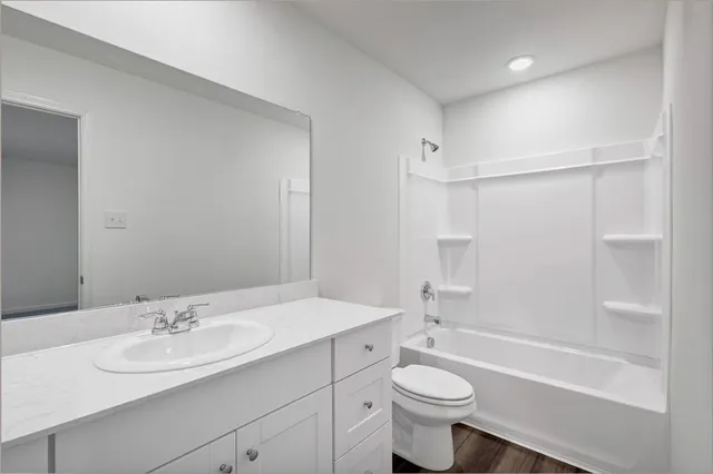 a bathroom with a bathtub shower sink vanity mirror and toilet