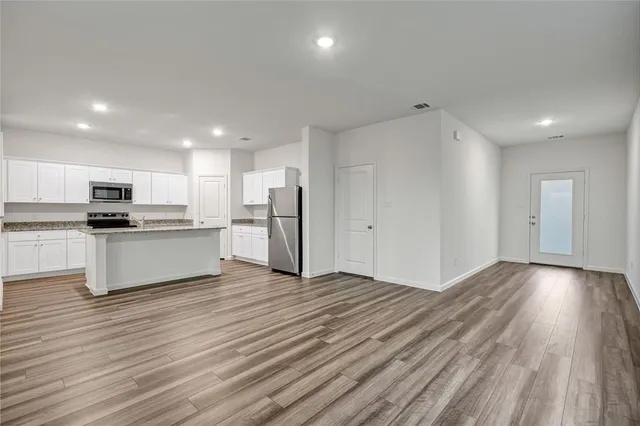 a view of kitchen view wooden floor and stainless steel appliances
