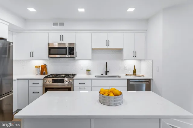 a kitchen with stainless steel appliances a stove a sink a refrigerator and cabinets