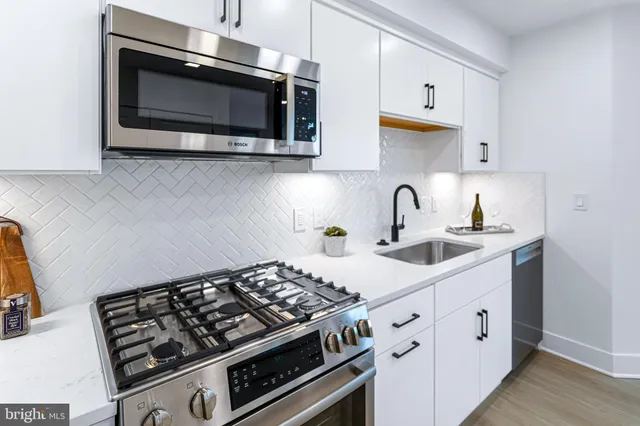 a kitchen with stainless steel appliances a sink a stove and cabinets