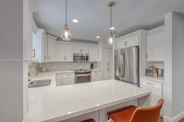 a kitchen with stainless steel appliances kitchen island granite countertop a refrigerator a stove top oven a sink a dining table and chairs with wooden floor